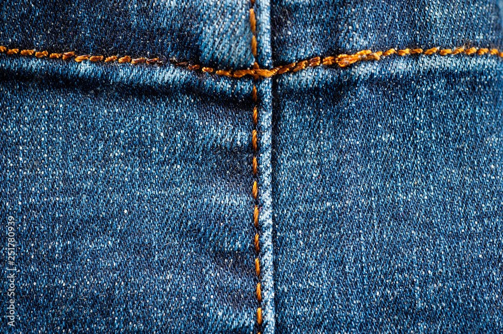 Fragment of a classic blue denim texture with orange stitching Fragment of a classic blue denim texture with orange stitching