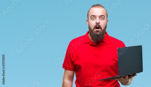 Young caucasian man using computer laptop over isolated background scared in shock with a surprise face, afraid and excited with fear expression