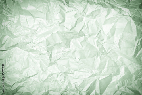 Texture of crumpled greenish paper, background. Photo with vignette.