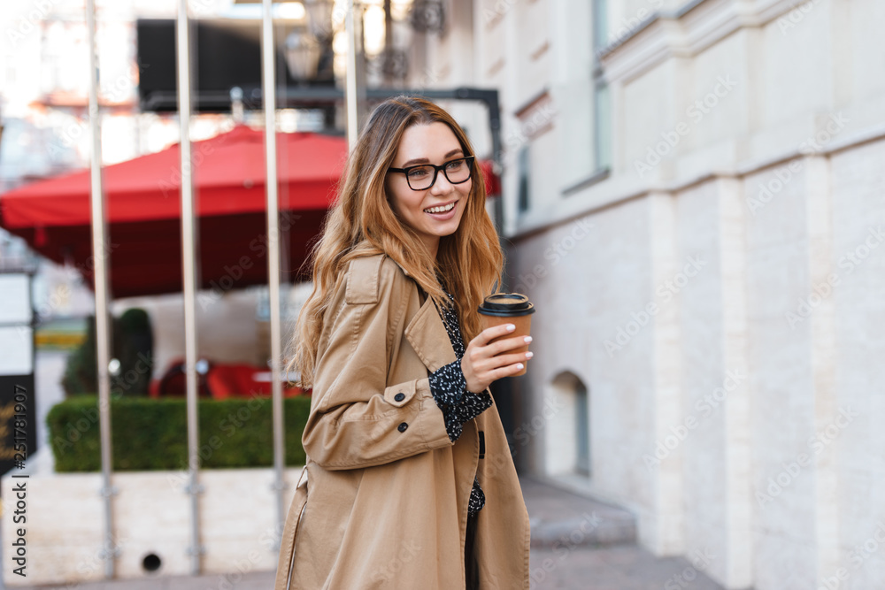 Portrait of lovely woman drinking takeaway coffee while walking through city street Portrait of lovely woman drinking takeaway coffee while walking through city street