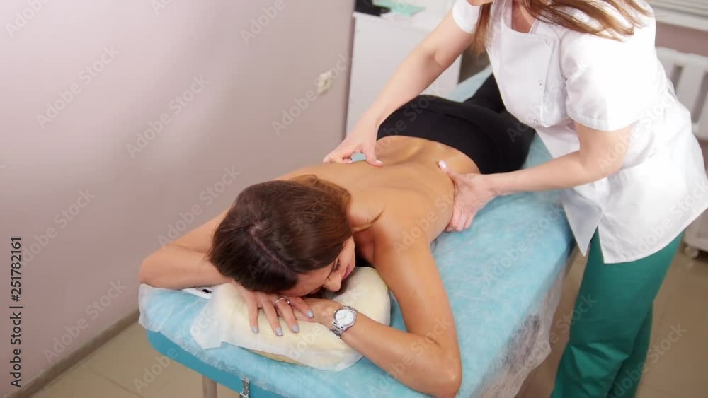 A young woman receiving a back massage in medical clinic A young woman receiving a back massage in medical clinic