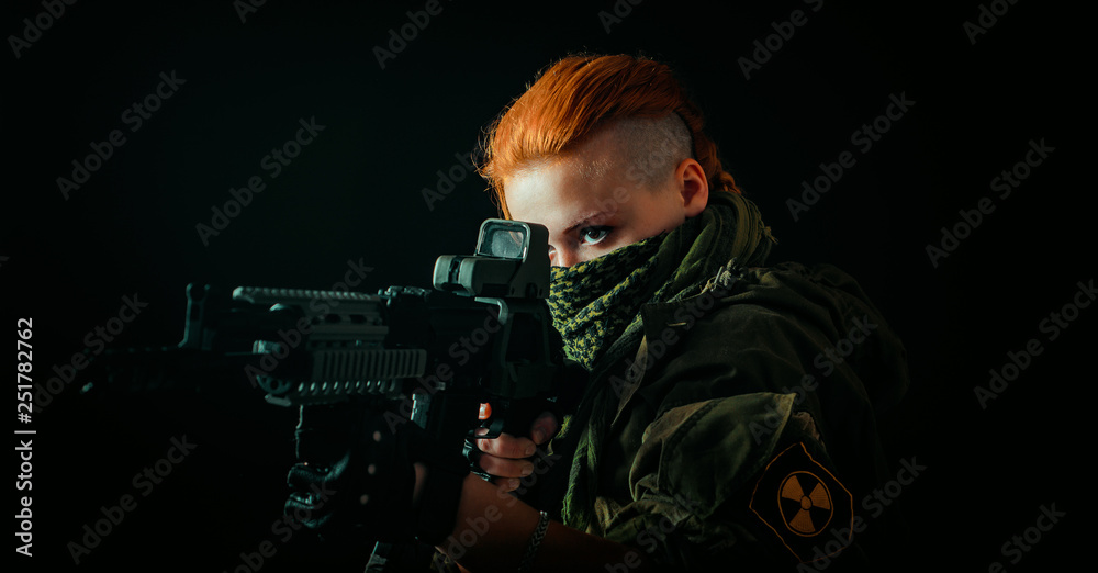 Young woman with red hair and girl with a bandage on his face, hold machinegun in military uniform.