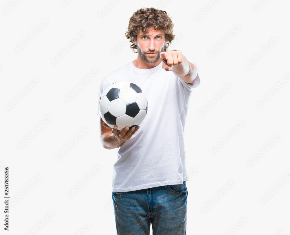 Handsome hispanic man model holding soccer football ball over isolated background pointing with finger to the camera and to you, hand sign, positive and confident gesture from the front