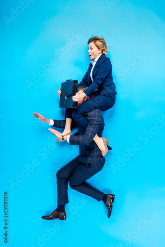 Man holding on shoulders shocked woman with briefcase on blue background