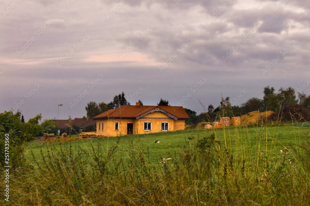 Rural  landscape with cloudy sky and red roof brick house. Hills landscape with dramatic sky as background. 