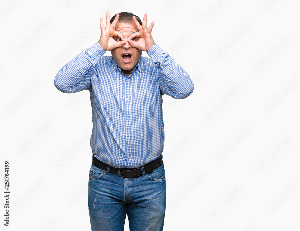 Fototapeta premium Middle age arab business man over isolated background doing ok gesture like binoculars sticking tongue out, eyes looking through fingers. Crazy expression.