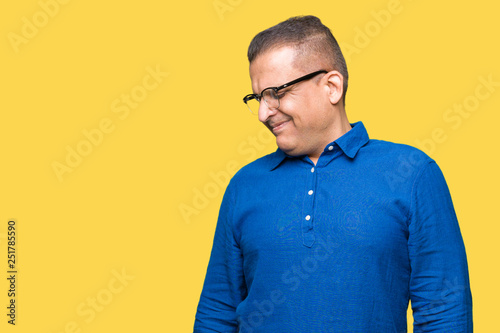 Middle age arab man wearing glasses over isolated background looking away to side with smile on face, natural expression. Laughing confident. © Krakenimages.com