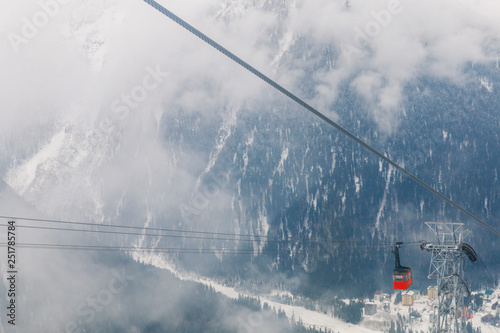 Red Ski lift in the background of the winter mountains. The red trailer of the old cable car moves to the mountain top of the ski resort. Retro gondola.