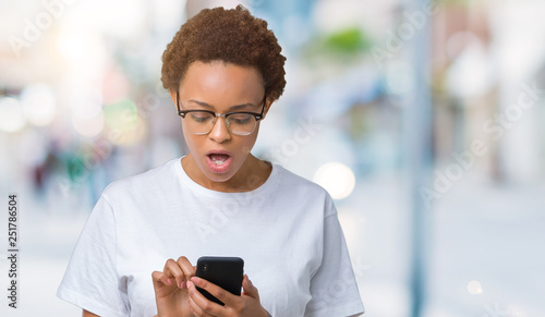 Young african american woman using smartphone over isolated background scared in shock with a surprise face, afraid and excited with fear expression