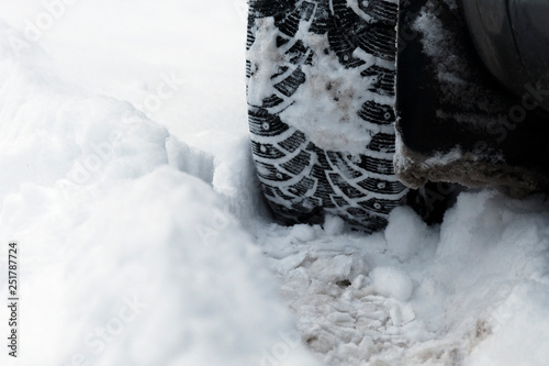 Car wheel with winter studded tires on  background of snow. © Alsu