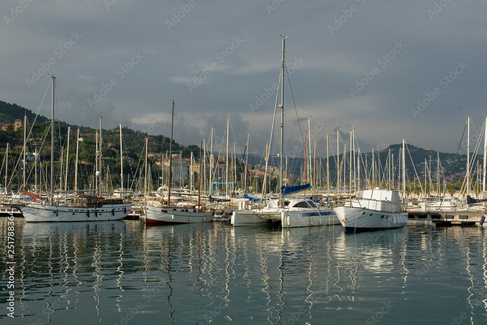 view of harbor, marina, port with sailing boats, catamarans, motorboats and yachts, sunset, sun, holidays, travel, mediterranean, Imperia, Liguria, Italy