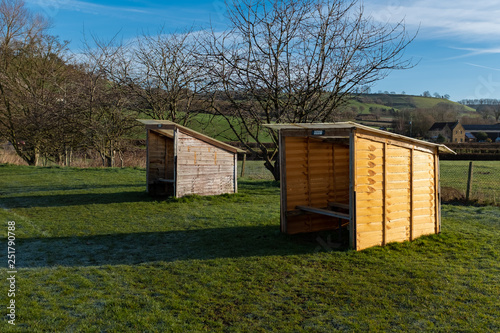Two small rustic football dugouts in a field