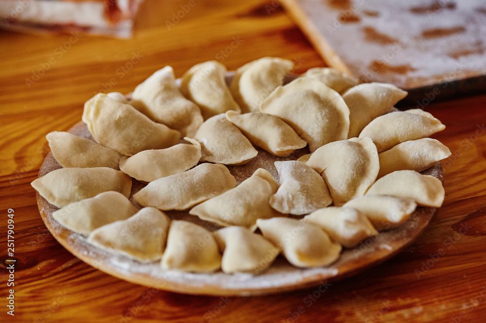 Dumplings raw on a wood board. The process of cooking Dumplings raw on a wood board. The process of cooking