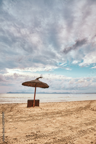 Sun umbrella on an empty beach, color toning applied. © MaciejBledowski