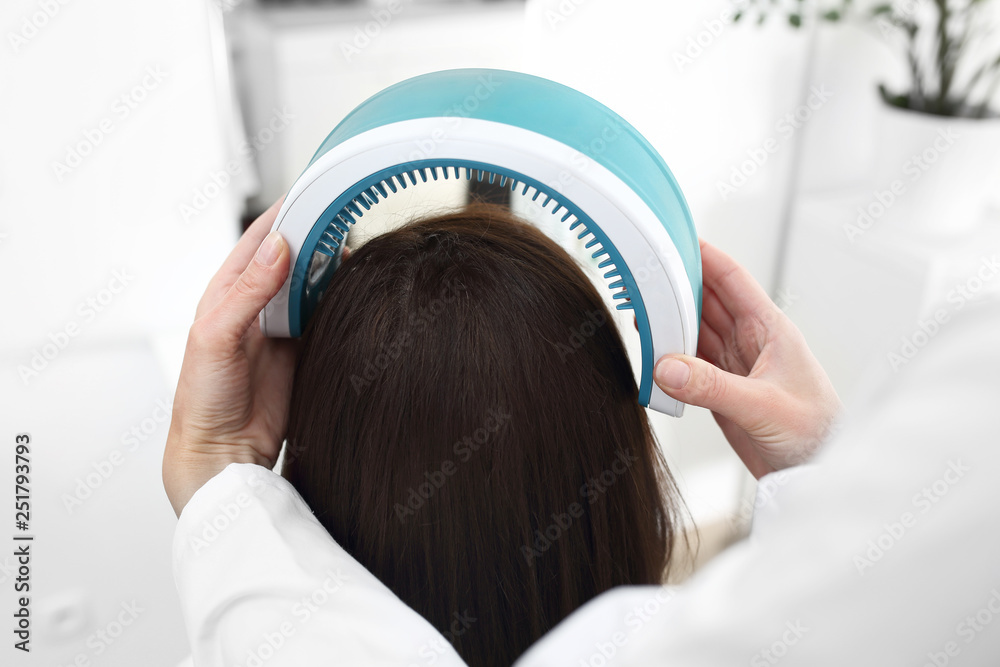 Fototapeta premium Laserowa terapia skóry głowy i włosów. Kobieta z cienkimi i słabymi włosami na zabiegu w gabinecie lekarskim.