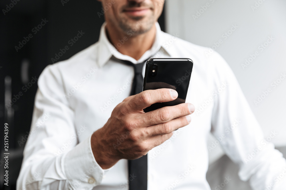 Business man in bedroom indoors at home sitting on bed using mobile phone. Business man in bedroom indoors at home sitting on bed using mobile phone.