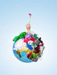 An earth globe covered with trash and male hand with a withering flower over white background, the concept of ecology problem and World Environment Day. Photo with message for social advertising