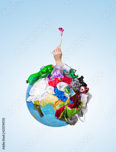 Fototapeta Naklejka Na Ścianę i Meble -  An earth globe covered with trash and male hand with a withering flower over white background, the concept of ecology problem and World Environment Day. Photo with message for social advertising