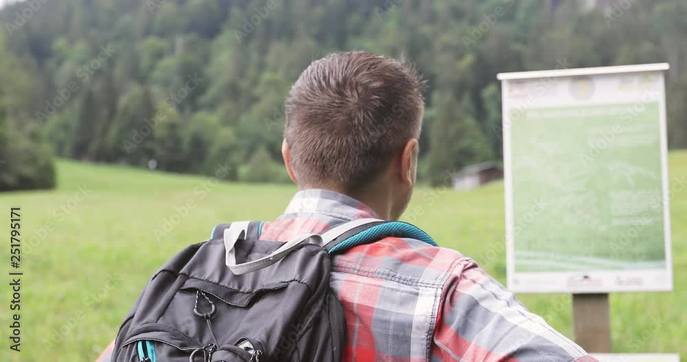 Adult man with a backpack reads pointers in the mountains. Adult man with a backpack reads pointers in the mountains.