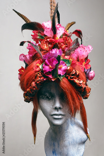 Mannequin in creative wig with flowers and feathers 