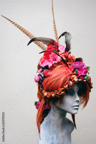 Mannequin in creative wig with flowers and feathers  photo