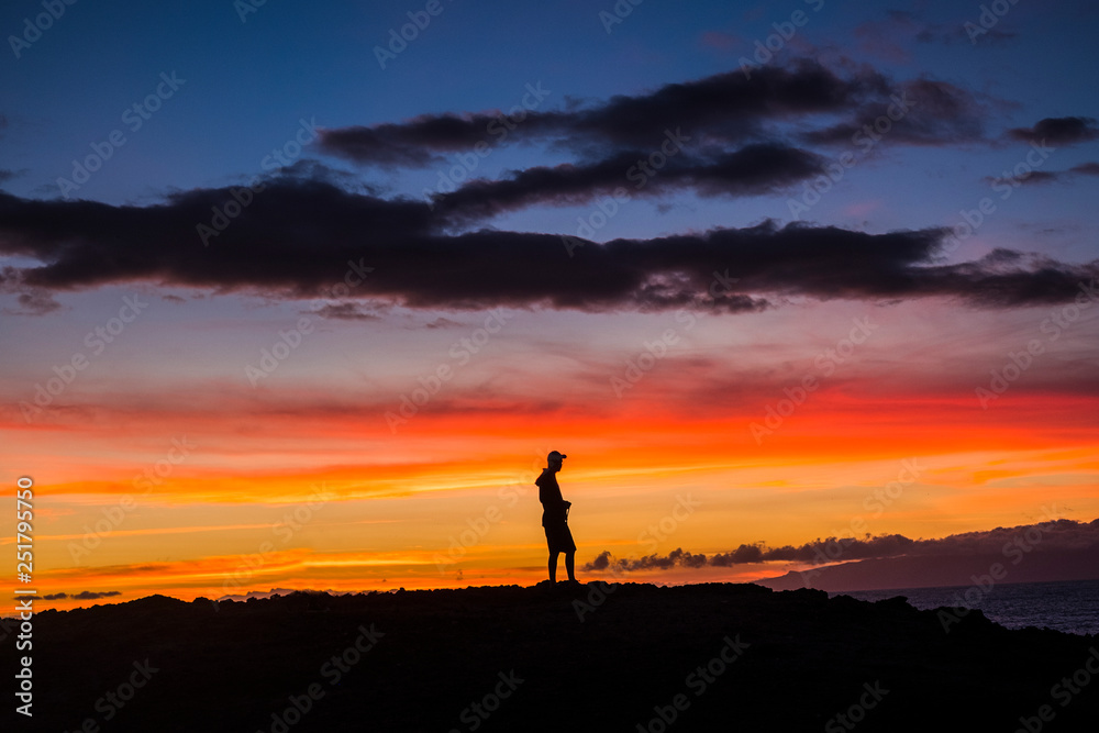 Man standing outdoor looking and enjoying the romantic sunset - feeling the nature and happiness for free lifestyle - people and outdoor show with coloured clouds in the dawn time