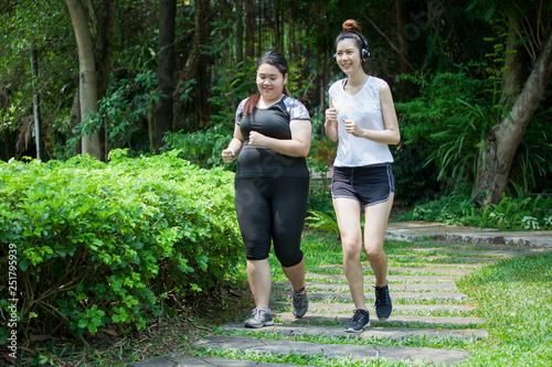 Fototapeta Naklejka Na Ścianę i Meble -  Asian Thin and overweight woman jogging in park, fat and fitness girls running workout together,exercises,sport,healthy lifestyle