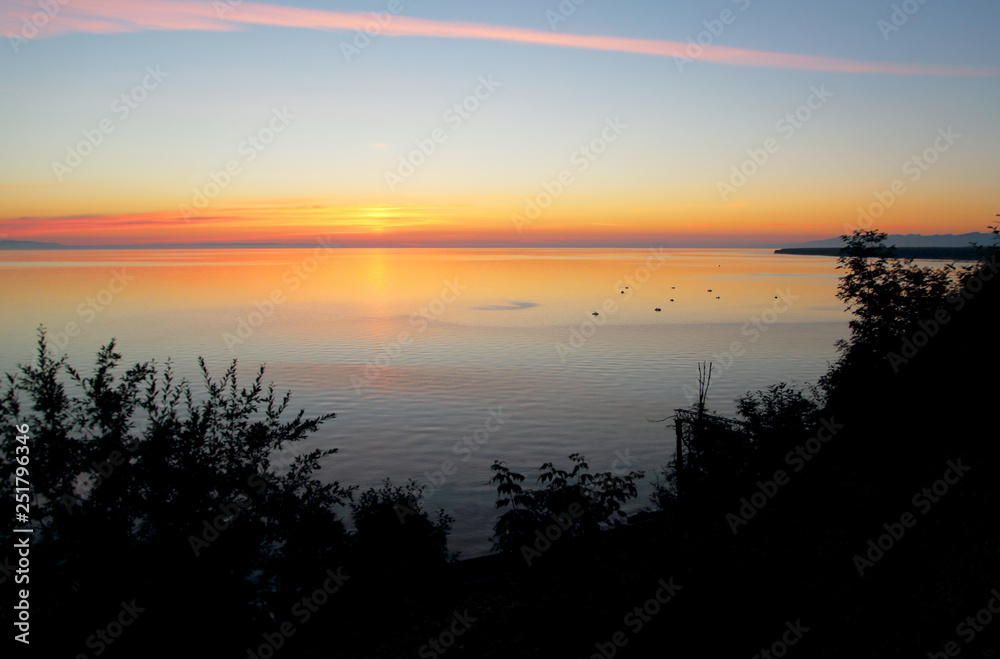 On the morning dawn on the surface of lake Baikal in the distance can be seen boats with fishermen – in this place in the summer a traditional place for fishing on the Baikal omul and grayling