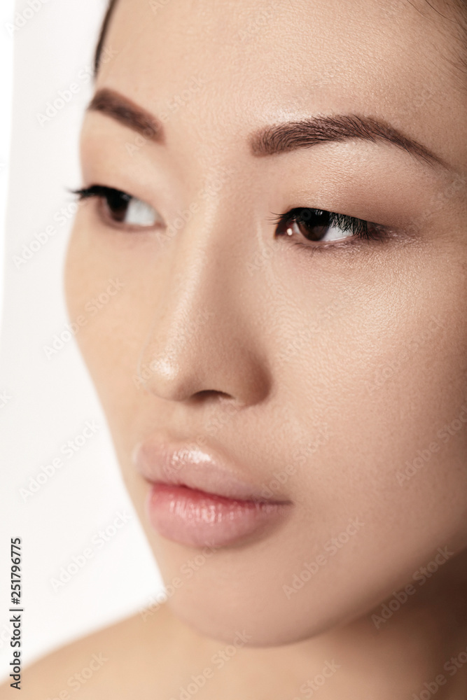 close-up portrait of beautiful young asian woman on white background closeup. girl with clean skin. Female lips after augmentation procedure close-up portrait of beautiful young asian woman on white background closeup. girl with clean skin. Female lips after augmentation procedure