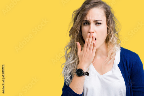 Beautiful young blonde woman over isolated background bored yawning tired covering mouth with hand. Restless and sleepiness.
