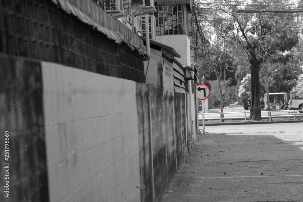 Retro turn left traffic sign in bright color on black and white background small street alley in urban city area.  Concept of hope to exit from sadness, bad situation or depression.