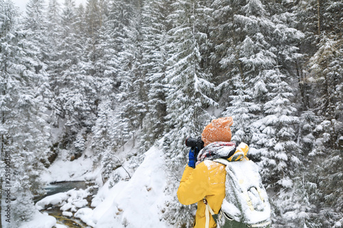 The photographer in winter forest in mountains