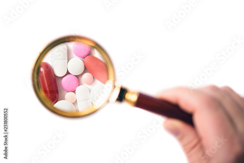 Canvas Print pills under a magnifying glass on the white background