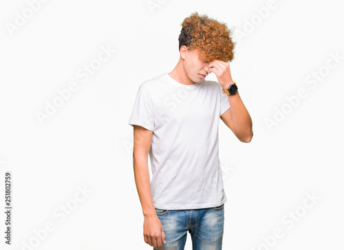 Young handsome man with afro hair wearing casual white t-shirt tired rubbing nose and eyes feeling fatigue and headache. Stress and frustration concept.