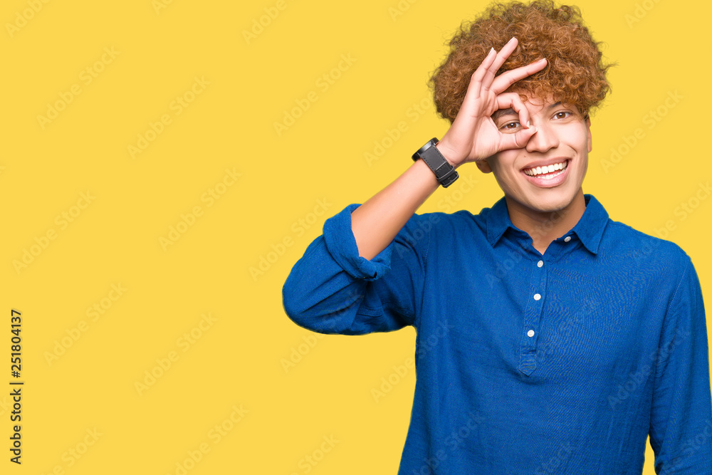 Young handsome elegant man with afro hair doing ok gesture with hand smiling, eye looking through fingers with happy face. Young handsome elegant man with afro hair doing ok gesture with hand smiling, eye looking through fingers with happy face.