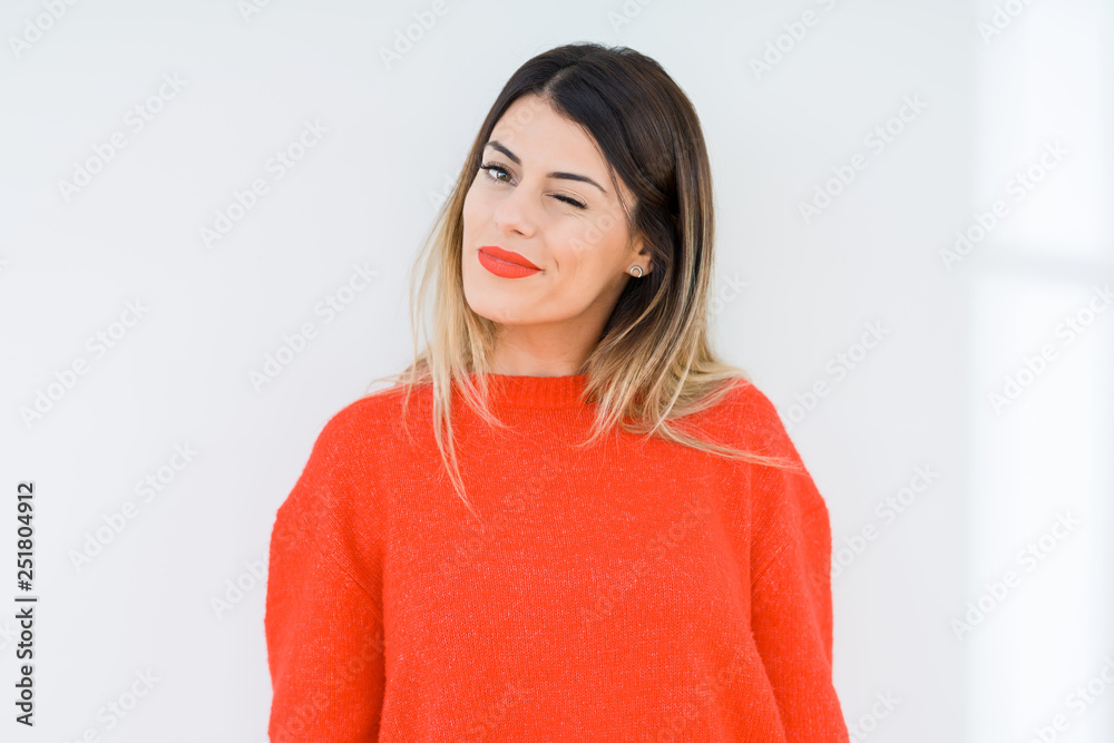Young woman wearing casual red sweater over isolated background winking looking at the camera with sexy expression, cheerful and happy face. Young woman wearing casual red sweater over isolated background winking looking at the camera with sexy expression, cheerful and happy face.