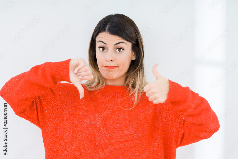 Young woman wearing casual red sweater over isolated background Doing thumbs up and down, disagreement and agreement expression. Crazy conflict Young woman wearing casual red sweater over isolated background Doing thumbs up and down, disagreement and agreement expression. Crazy conflict
