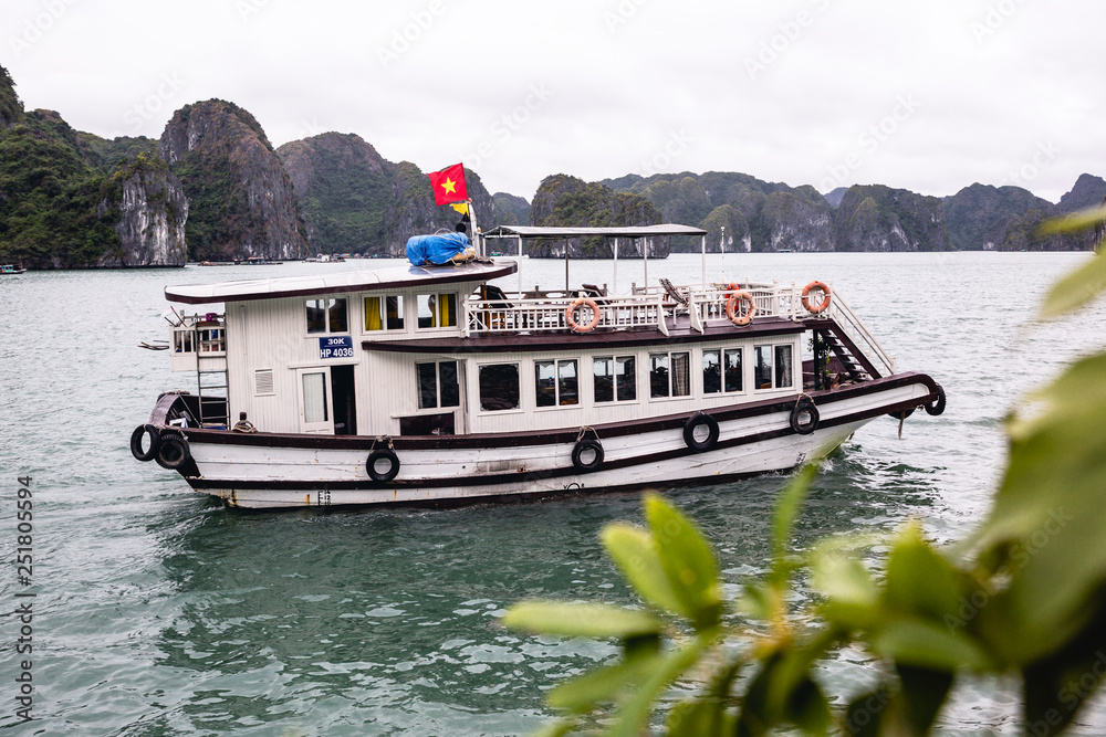 Boat trip in wintertime, Halong Bay, Vietnam, Asia, white wooden boat with Vietnamese red flag Boat trip in wintertime, Halong Bay, Vietnam, Asia, white wooden boat with Vietnamese red flag
