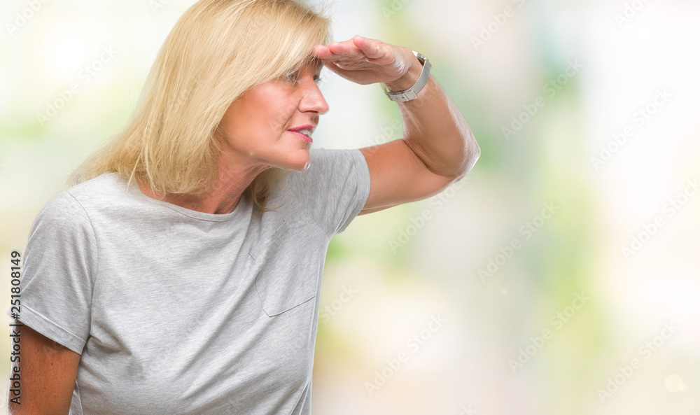 Middle age blonde woman over isolated background very happy and smiling looking far away with hand over head. Searching concept. Middle age blonde woman over isolated background very happy and smiling looking far away with hand over head. Searching concept.