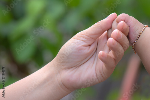 Baby hand gently holding adult's finger, New family and baby protection from mom concept