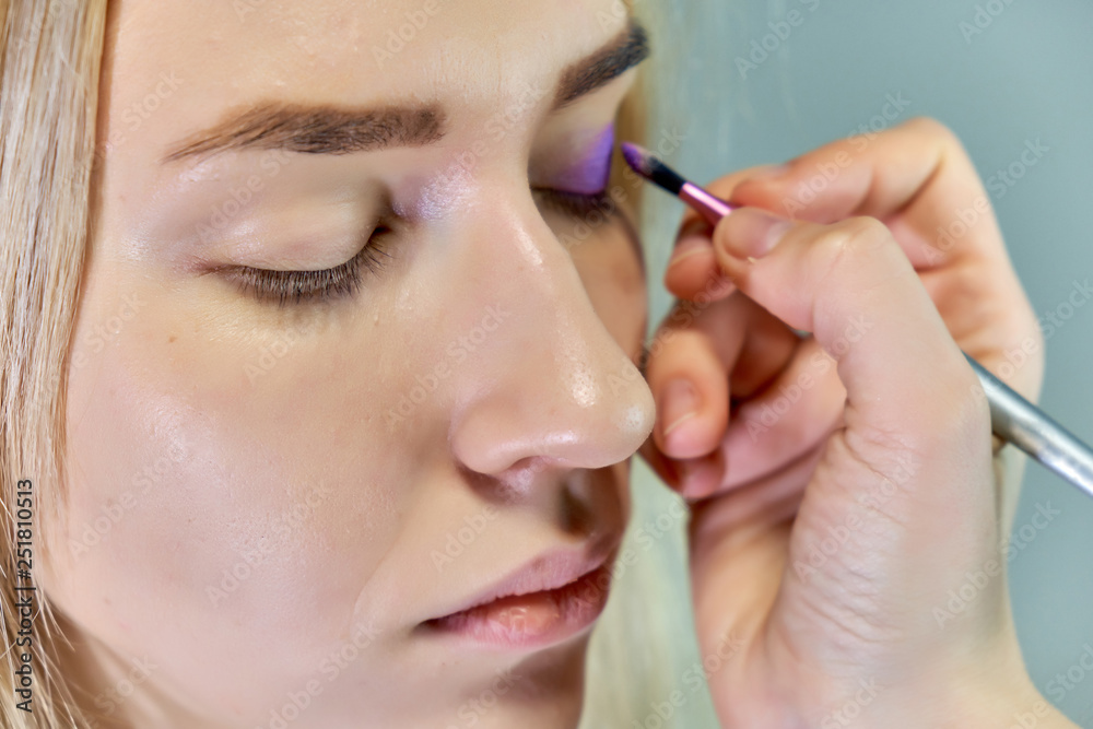 Concept work of a beautician cosmetologist in with office. Makes hair, applies makeup on a gray background. Concept work of a beautician cosmetologist in with office. Makes hair, applies makeup on a gray background.