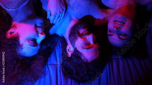 Three people lying in bed talking and smiling.Love for three, polygamy
