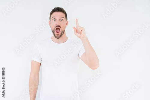 Young handsome man wearing casual white t-shirt over isolated background pointing finger up with successful idea. Exited and happy. Number one.