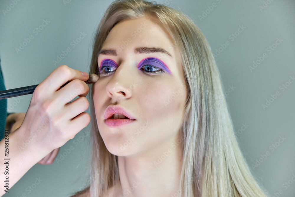 Concept work of a beautician cosmetologist in with office. Makes hair, applies makeup on a gray background. Concept work of a beautician cosmetologist in with office. Makes hair, applies makeup on a gray background.