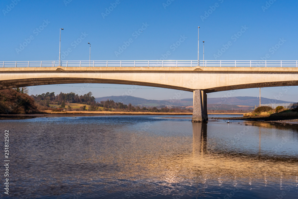 Concrete arch bridge reflecting in the Vartry river, Broad Lough, illuminated by the morning sun in Wicklow, Ireland. Concrete arch bridge reflecting in the Vartry river, Broad Lough, illuminated by the morning sun in Wicklow, Ireland.