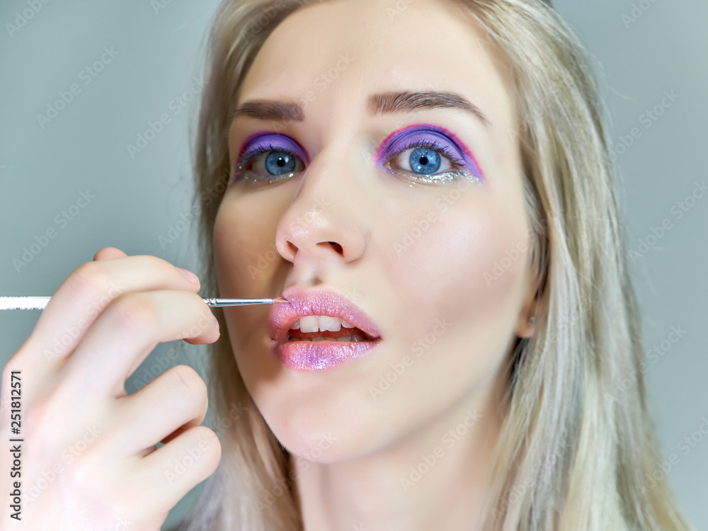 Concept work of a beautician cosmetologist in with office. Makes hair, applies makeup on a gray background. Concept work of a beautician cosmetologist in with office. Makes hair, applies makeup on a gray background.