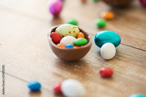 easter, junk-food, confectionery and unhealthy eating concept - close up of chocolate egg and candy drops on table