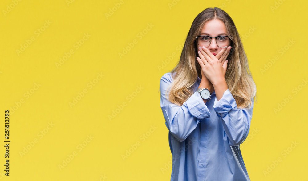 Young beautiful blonde business woman wearing glasses over isolated background shocked covering mouth with hands for mistake. Secret concept. Young beautiful blonde business woman wearing glasses over isolated background shocked covering mouth with hands for mistake. Secret concept.