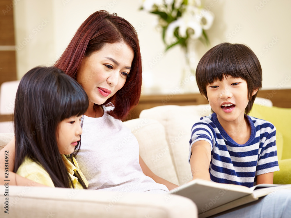 asian mother and two children reading a book at home asian mother and two children reading a book at home