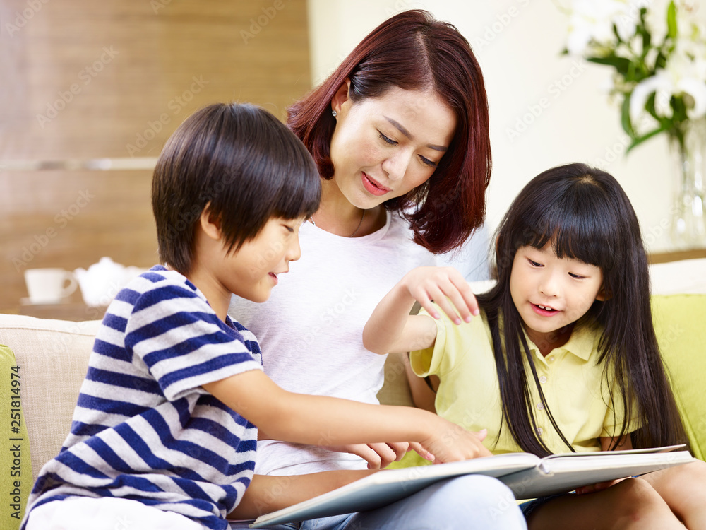 asian mother and two children reading a book at home asian mother and two children reading a book at home